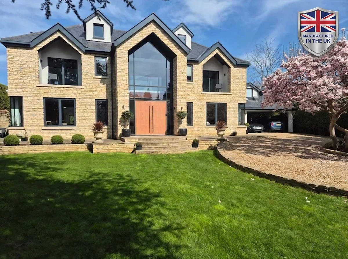 Large house with a well-maintained garden and cherry blossom tree, featuring a 'Manufactured in the UK' badge.